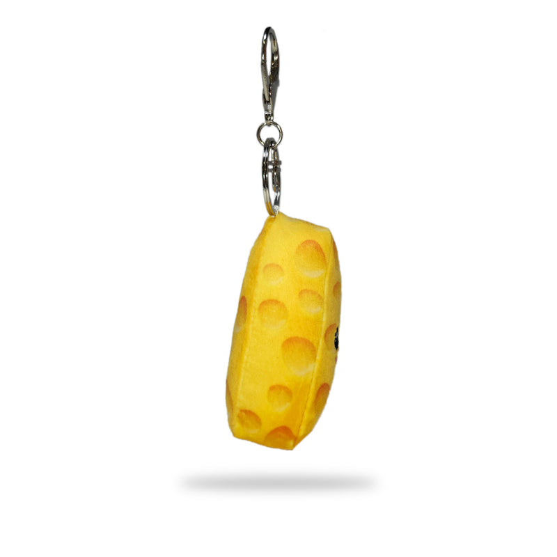 Side view of a yellow plush cheese wedge keychain with textured holes and a silver key ring clip, on a white background.