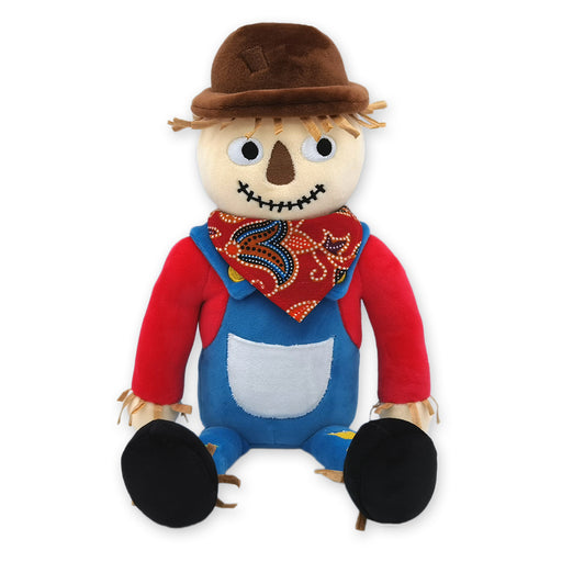 A plush scarecrow with a brown hat, red shirt, blue overalls, and black boots. It has a smiling face and is designed to look fluffy and soft.