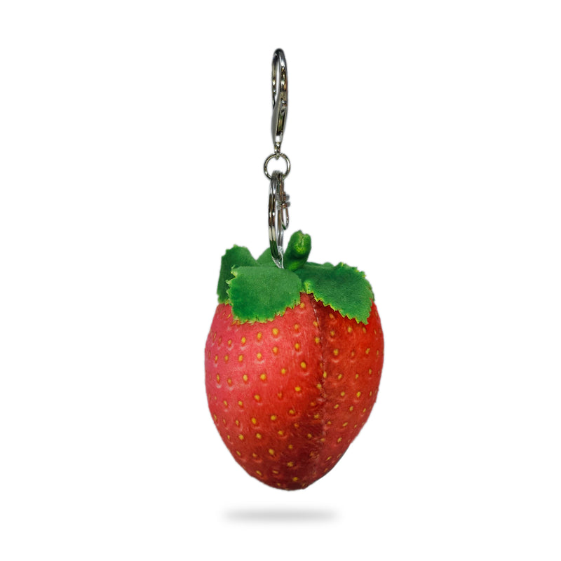 Side view of a plush strawberry keychain with red fabric, yellow seed details, green felt leaves on top, and a silver key ring clip, on a white background.