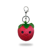 Front view of a plush strawberry keychain with red fabric, green felt leaves, stitched smiling face, and a silver key ring clip, on a white background.