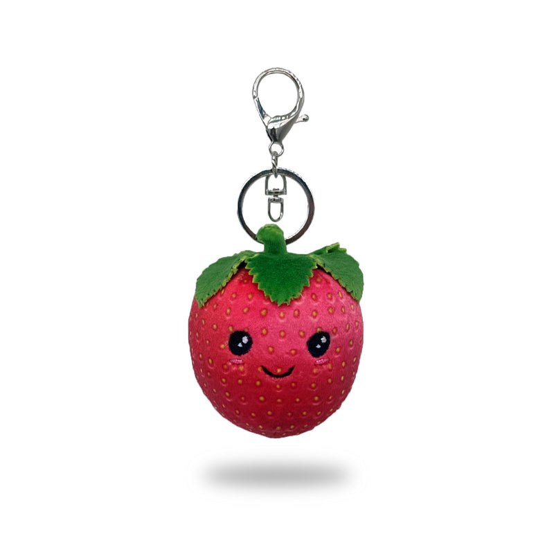 Front view of a plush strawberry keychain with red fabric, green felt leaves, stitched smiling face, and a silver key ring clip, on a white background.