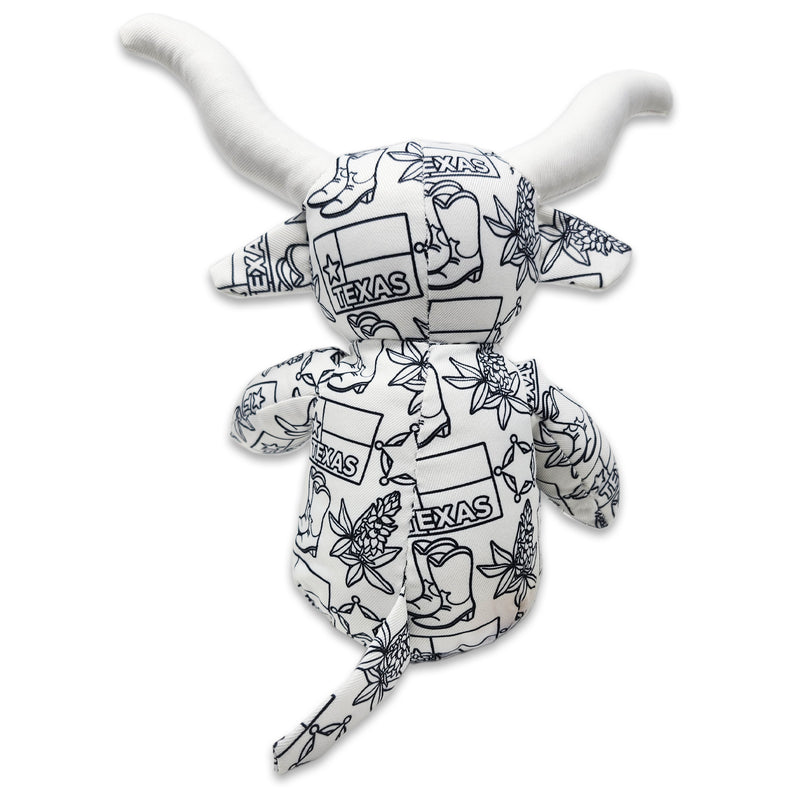 Back view of a white longhorn cow plush covered in black Texas-themed line illustrations, including the word “Texas,” with long horns, small tail, and printed pattern visible across the head and body.