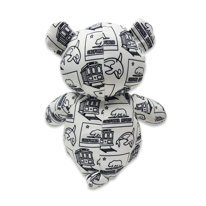 Back view of a white teddy bear plush covered in black California Republic illustrations.
