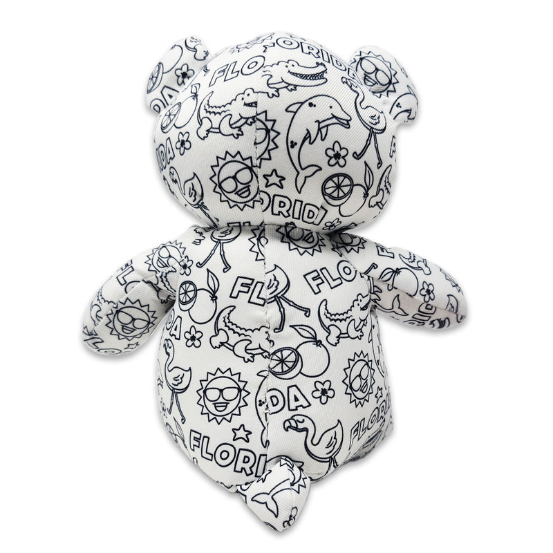 Back view of a white teddy bear plush covered in black Florida-themed illustrations, including alligators, dolphins, flamingos, suns, oranges, and the word Florida.