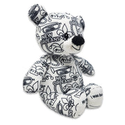 Angle view of a black-and-white colorable plush bear printed with New Orleans text, fleur-de-lis symbols, trumpets, beads, and city-themed designs.