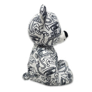 Side view of a black-and-white colorable plush bear printed with New Orleans text, fleur-de-lis symbols, trumpets, beads, and city-themed designs.