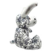 Side view of a white longhorn cow plush covered in black Texas-themed line illustrations, including the word “Texas,” with stitched text reading “My name” on one foot and “I was born” on the other.