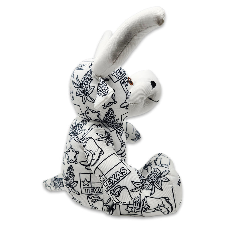 Side view of a white longhorn cow plush covered in black Texas-themed line illustrations, including the word “Texas,” with stitched text reading “My name” on one foot and “I was born” on the other.