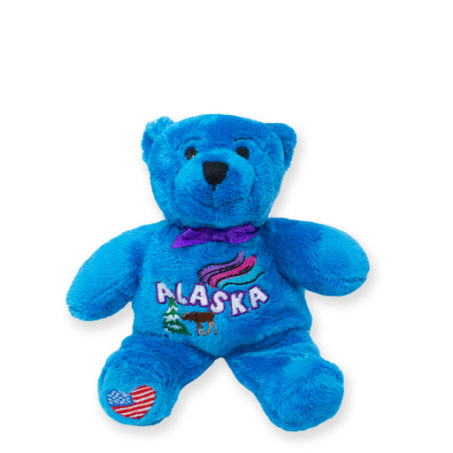 A plush blue bear with 'Alaska' embroidered on its chest, featuring a small American flag and a purple bow tie.