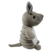 Side view of a gray plush armadillo with upright ears, stitched black eye, segmented body bands, white belly, and long tail on a transparent background.