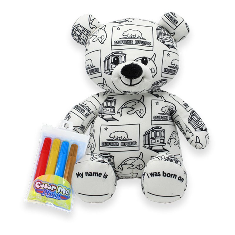 Front view of a white teddy bear plush covered in black California-themed illustrations, with a Color Me Plush marker pack shown beside it and text on the feet reading “My name is” and “I was born on.”
