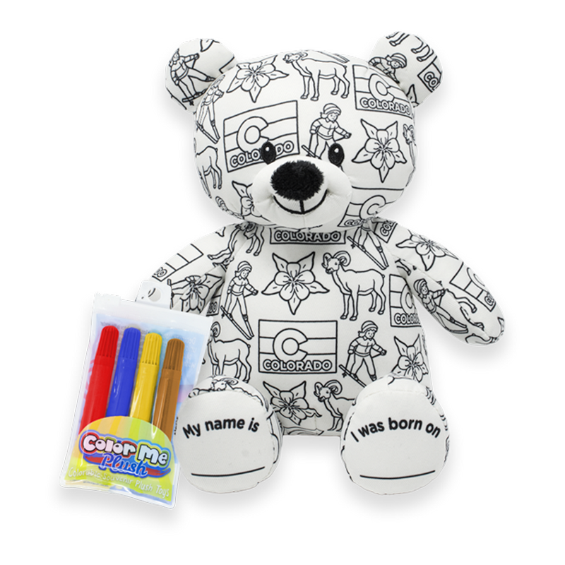 Front view of a white teddy bear plush covered in black Colorado-themed illustrations, with a Color Me Plush marker pack shown beside it, and text on the feet reading “My name is” and “I was born on.”