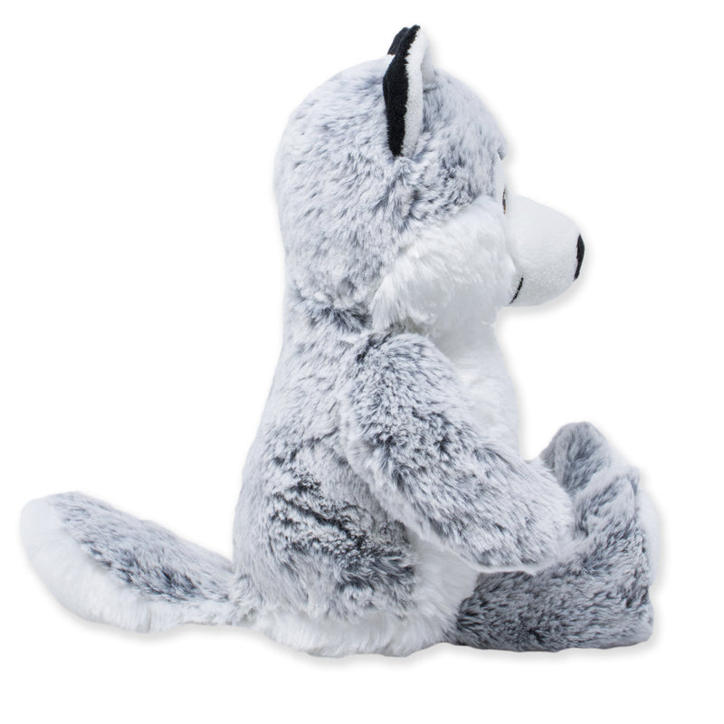 Side view of a gray and white plush husky dog with fluffy fur, pointed ears, a long tail, and seated legs, shown against a white background.