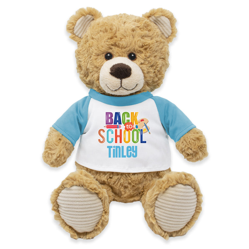 A brown plush teddy bear wearing a blue t-shirt with the text 'BACK TO SCHOOL TILLEY'.