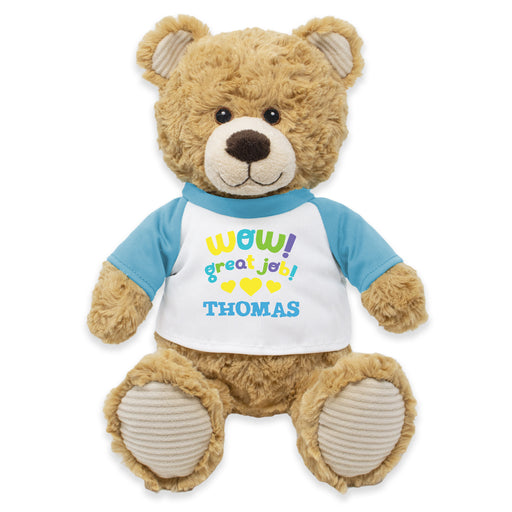 A plush teddy bear wearing a white shirt with a blue and yellow bow tie, and the text 'WOW! GREAT JOB, THOMAS!' printed on it.